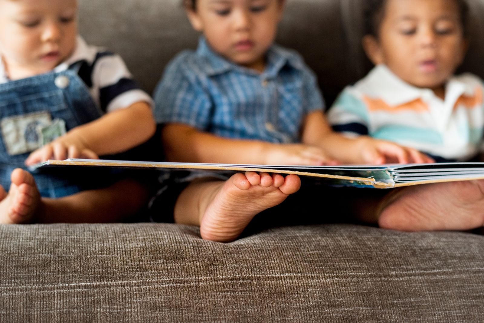 MRA ARTICLES 1600 X 1067 A photo of three kids reading a book to illustrate the article "ocean books for babies and toddlers"